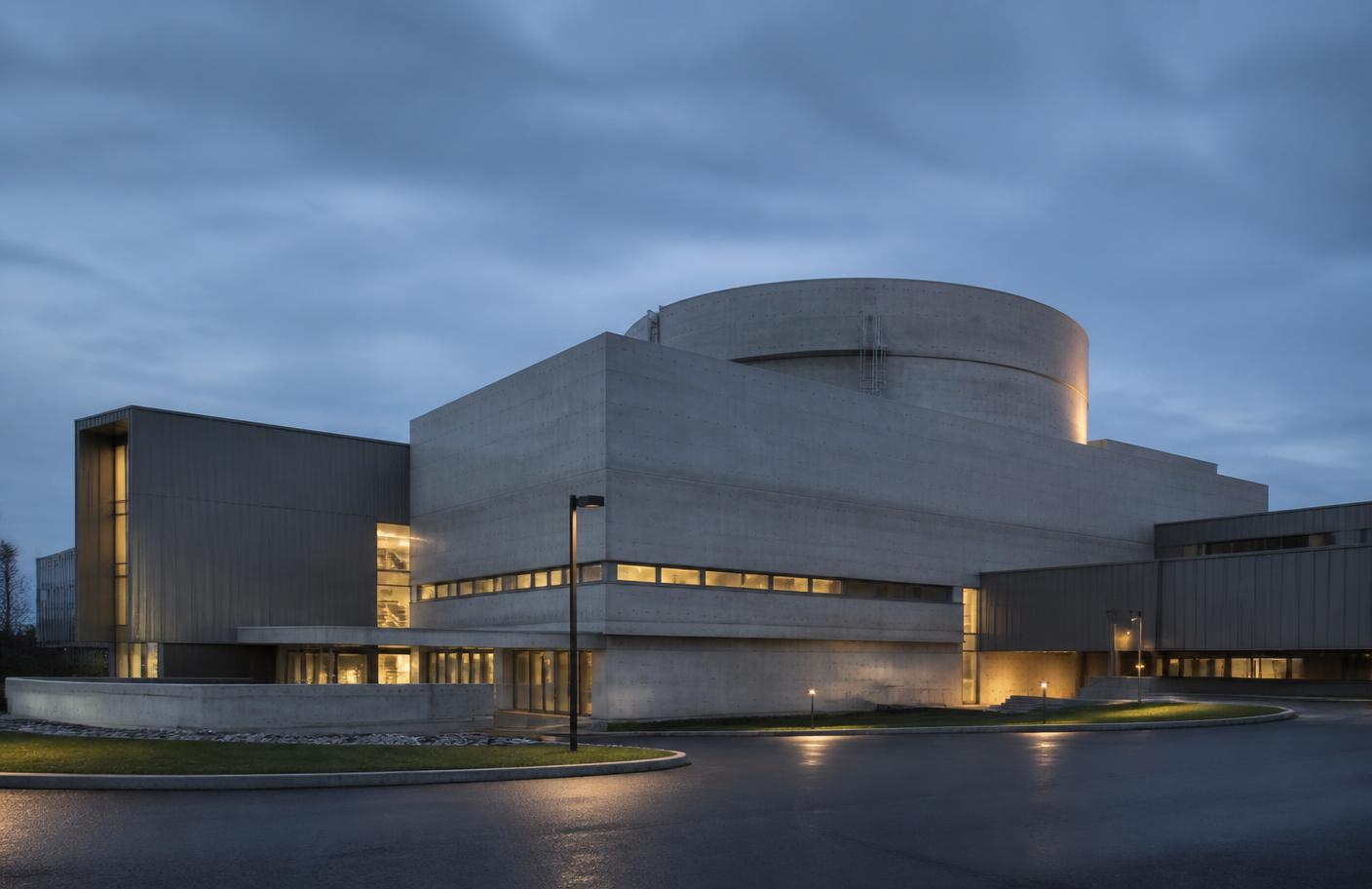Exterior of a modern nuclear facility at dusk with clean concrete forms and site lighting
